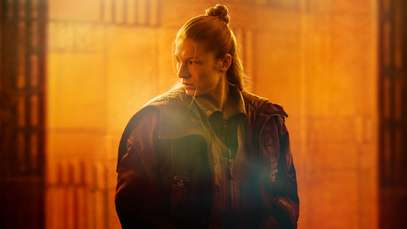 Rollfigur i sliten skinnjacka i orange ljus ur Blade Runner 2099
